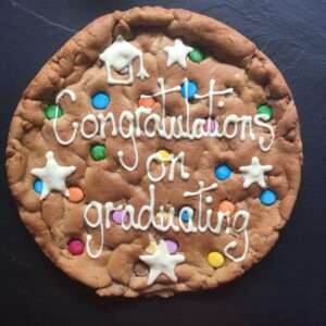Let’s celebrate in style with our delicious, limited addition Graduation Cookie. A perfect gift to show that special someone how proud you are of their achievement. Whether it be a University graduate, Primary or secondary School graduate, Nursery School graduate or a celebration of completing a school year, this cookie will certainly put a smile on their face. Preset design with stars, graduation hat ‘mortarboard’ and rainbow coloured chocolate beans for that added fun factor. Available in a variety of flavours: Double Chocolate Available in Gluten Free Not available in Vegan Free message in the box as standard. Gift wrap options are available for that extra gifting luxury. Additional fee’s apply Serves 10, approximate weight 650g. Image example shows – Double Chocolate
